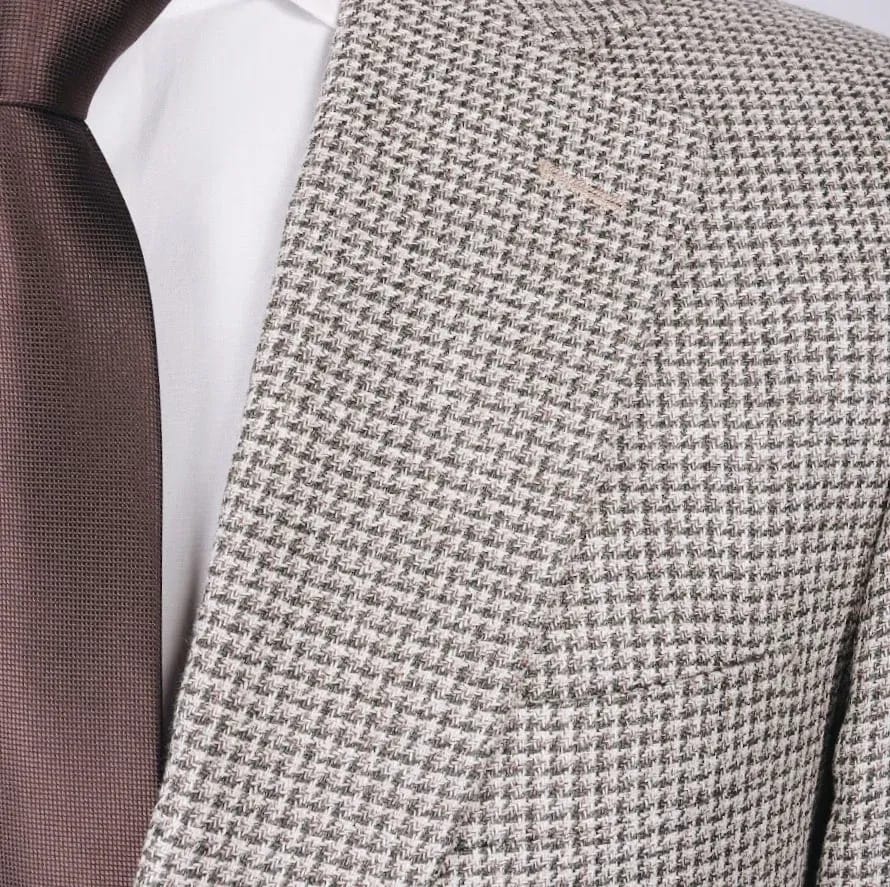 Крупный план лацкана пиджака из светло-бежевой ткани с мелким рисунком