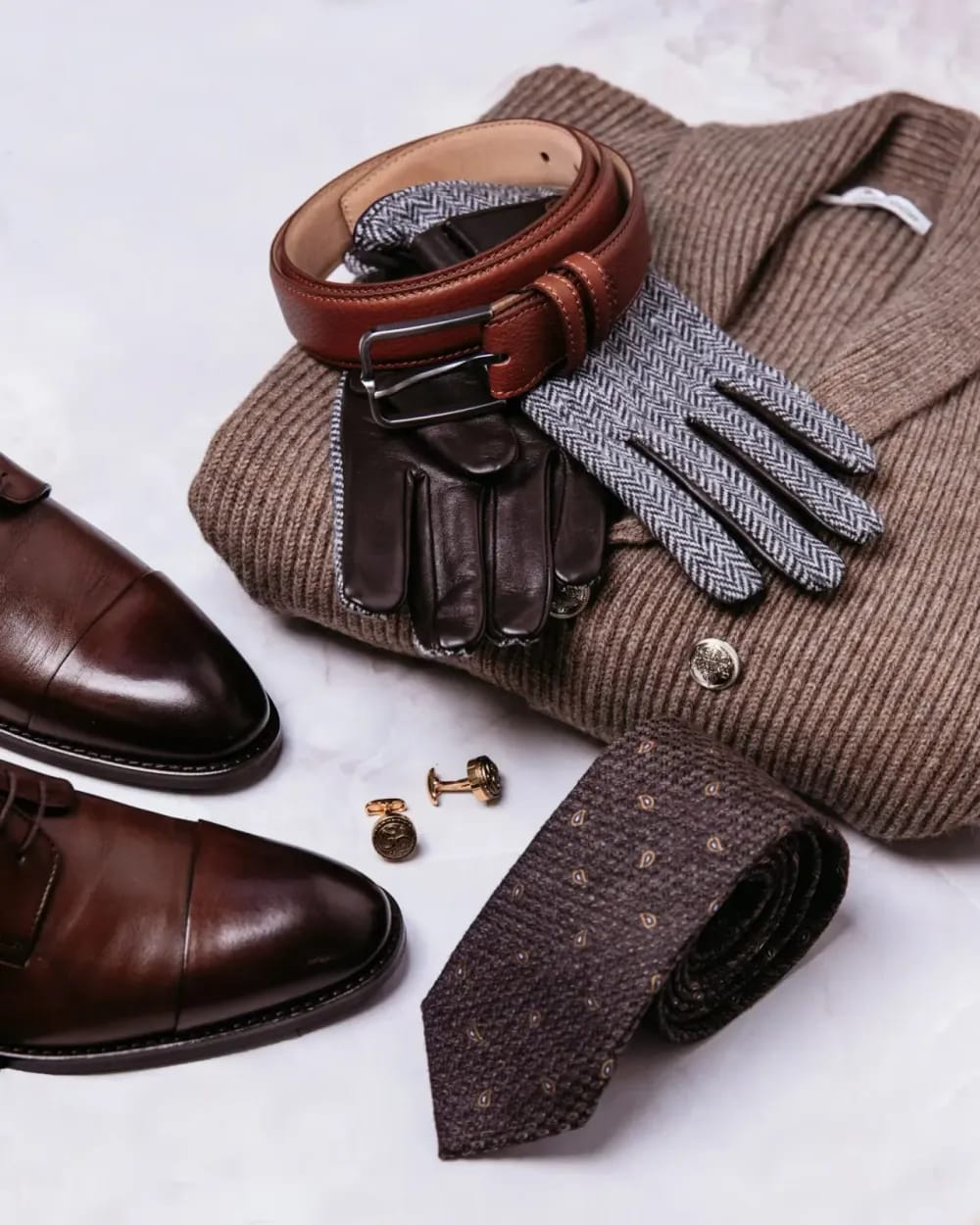 Flat-lay: свитер, ремень, перчатки, запонки, галстук и туфли на светлом фоне