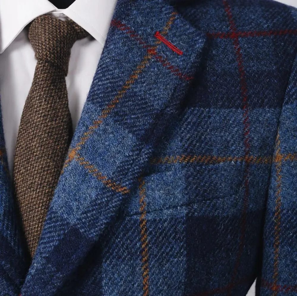 Крупный план лацкана пальто из синего Harris Tweed с крупной клеткой в красно-рыжих тонах, коричневый твидовый галстук