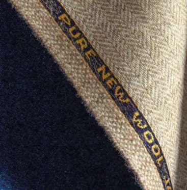 Крупный план двух отрезов ткани Pure New Wool — тёмно-синего и бежевого