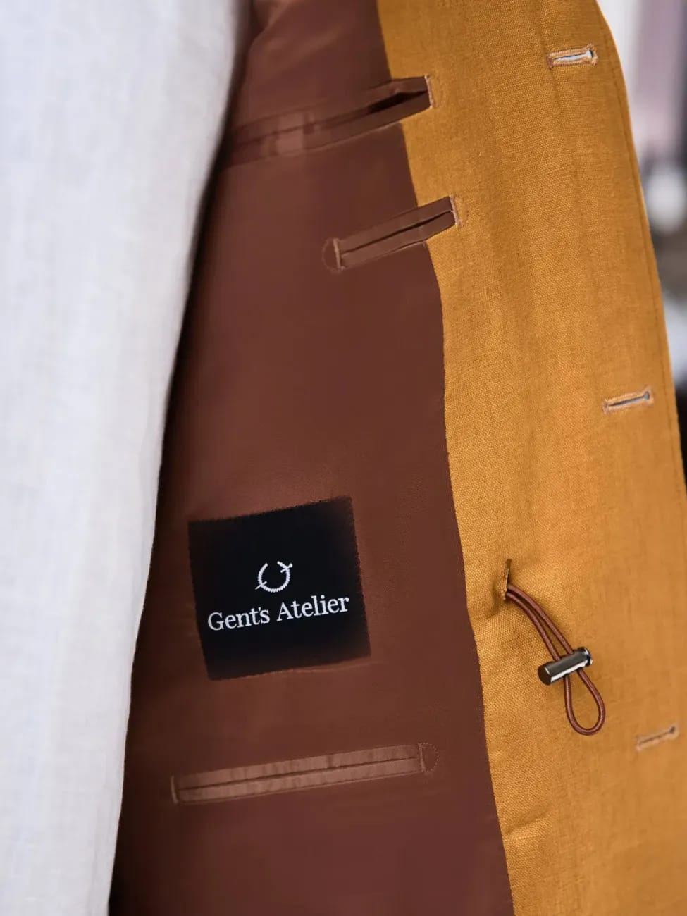 Подкладка горчичного льняного пиджака с лейблом Gent's Atelier и коричневой шёлковой подкладкой