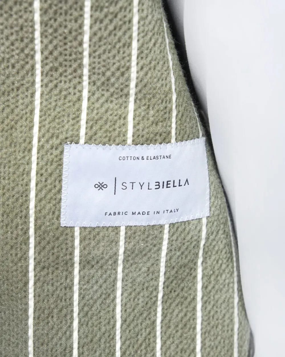 Этикетка Stylbiella Cotton & Elastane на зелёной ткани в полоску